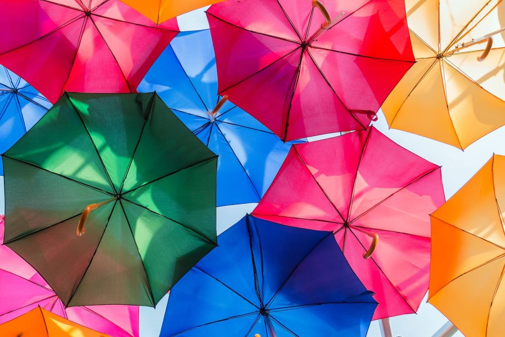 A dozen umbrellas in primary colors are spread open and photographed from underneath.